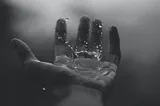 Time-lapse photo of rain splashing on open palm