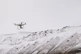 A drone flies above the arctic white mountains of Svalbard.