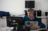 A guy working on his laptop and monitor display.