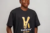 Ademola Joshua, Nigeria’s youngest CEO and influential developer, posing confidently in His KTA T-shirt, symbolizing his passion for technology and innovation