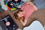 woman lying down with eyes closed listening to vinyl records