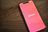 Smartphone on wooden table showing Tinder splash screen