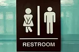 A restroom sign with a woman and man figure; woman is crossing her legs