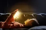 Girl layed on a bed and reading a book with glittery lights coming from it