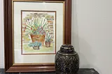 A large framed watercolor of 3 succulents and a black and gold urn sit on a gray side table