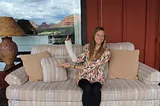 A young woman sitting on a couch holding up an arm in a cast