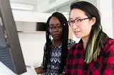 Two BIPOC women sitting at laptop.