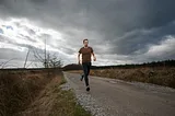 A man running away down a gravel road