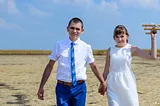 Young couple on honeymoon walking across a beach — Photo