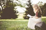 A woman reading a book in a field