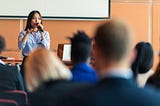 An Asian woman presenter interacting with the audience at a business presentation in the board room.