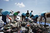 Group collecting trash from large pile on a beach