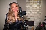 Mariah Carey singing into a mic for an event.