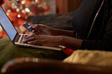 A person holds their credit card while online shopping on their laptop.