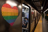 A pride colored heart is seen on a subway car near a person wearing a mask as the city moves into Phase 2 of re-opening following restrictions imposed to curb the coronavirus pandemic on June 25, 2020 in New York City.