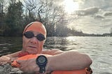 A selfie while swimming in the Thames, wearing goggles and an orange swim cap.