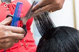A closeup photo of a hair stylist cutting a client’s hair.