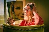 Photo of a late-middle aged woman reading a book called Everything a Teenage Girl Needs to Know