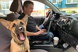 American Giant CEO Bayard Winthrop working on his laptop out of his truck with his 3-month-old puppy.