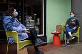 Friends wearing face masks practice social distancing as they chat in front of a shop during the outbreak of COVID-19.