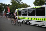Edward Breen riding a bike beside an ambulance