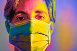 A multicolored closeup photo of a woman wearing a face mask.