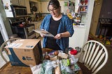 Emily Griffin reads a recipe for a Blue Apron meal while unpacking her box at her Lisbon Falls home.