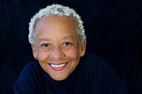 Portrait photo of Nikki Giovanni against a black background.