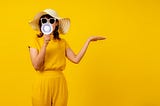 A lady with a handheld loudspeaker against a yellow background