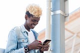 A side view of a non-binary African American person using their smartphone.