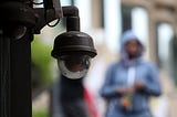 A video surveillance camera hangs from the side of a building in San Francisco, California.