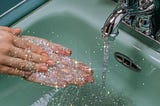 A photo of someone washing their hands in the sink. The water is glittery and sparkly.