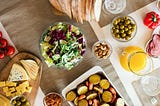 A table setting with healthy food. 9 Best Ways to Control Hunger by Lori Quayle