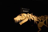 An large origami T-rex fossil, with a plaque that says “T-rex: Gilbert”