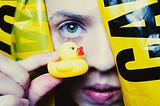 A person holding up a tiny yellow duck in front of their face