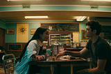 A photo still from the Netflix movie “To All the Boys I’ve Loved Before” that shows Lara Jean and Peter at a diner.