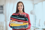 A girl happily holding a pile of clean laundry.