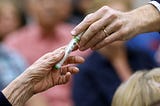 A close up shot of a woman’s hand passing on an insulin pen to Sen. Bill Cassidy (R-LA) during a town hall in 2017.