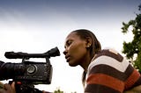 Black female journalist recording on her video camera.