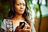 A photo of an annoyed black woman on her phone.
