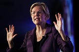 A photo of Elizabeth Warren with her hands raised.