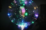A photo of a woman with an illuminated transparent ball in a dark room.