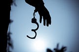 A photo of handcuffs being uncuffed on a person’s hand.