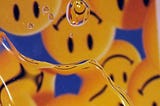 A photo of water droplets on glass with a reflection of upside down smiley face icons in the background.