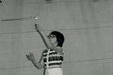 Black and white image from the mid 70’s of a girl in shorts and sleeveless top tossing a baton in the air