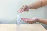 A photo of a person squirting hand sanitizer out of a bottle onto their hands.