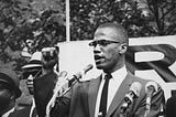 Malcolm X giving a speech at a rally.