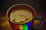 An image of a coffee cup partially illuminated with neon lights at the rim and handle with an image of the Authors face with a wry smile floating on top of the coffee inside the mug