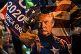 Trump supporter wears a shirt that has Trump as Captain America in front of American flag.