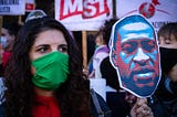 A woman wearing a face mask holds up a sign of George Floyd at a protest in Buenos Aires, Argentina.